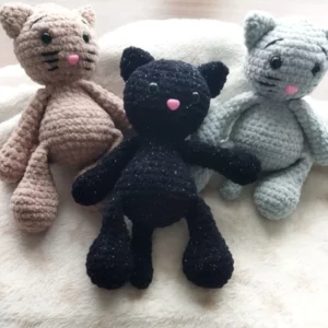 trois chats au crochet alignés sur une couverture